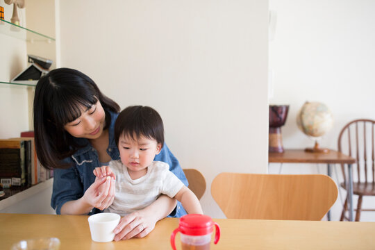 ダイニングテーブルで子供におやつを食べさせようとする母親