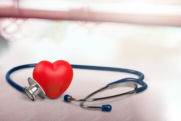 Red heart with medical stethoscope on desk