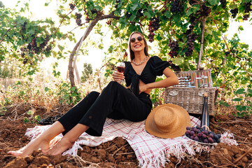 Young blonde woman sitting on a picnic in a vineyard