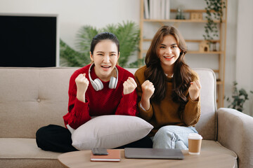 Two asian beauty smiling young women sitting on sofa Attractive casual girl feel happy and relax,having fun watch comedy video on TV in house. Activity lifestyles concept.