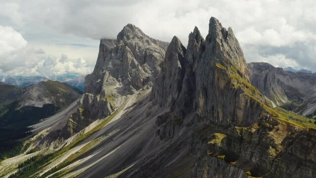 Tourist observation point overlooking Seceda ridgeline stretching in Italian Alps. Giant rocky mountain range against cloudy sky aerial view