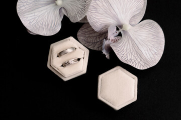 Gold wedding ring detail on black isolated background. with white orchid flowers
