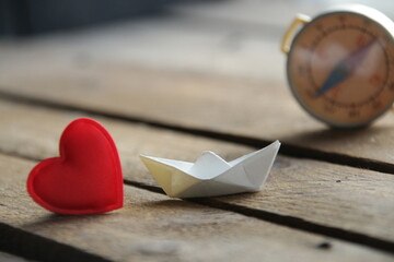 Red heart on a wooden background and paper boat. Place for text. Valentine. © Markgraf Ave