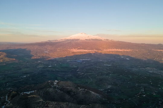Aerial view of Etna Volcano at sunset with snow on the peak in winter, Sicily, Italy.
