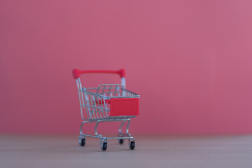 Empty shopping cart on pink background On wooden background. Shopping, online shopping, copy space.