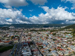 Obraz premium Aerial view of colorful mountain village of San Cristobal de Las Casas in Mexico. Clouds over the mountains. Panorama.