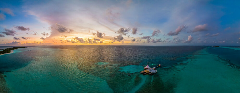 Panoramic aerial view of Huluwalu Island with luxury resort at sunset, Maldives archipelagos.