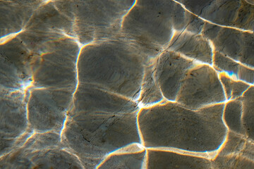 Colorful sun glare on the water in the fountain with an old stone floor, unusual abstract texture