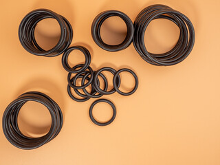 Hydraulic and pneumatic o-rings in black in different sizes on an orange background. Rubber gaskets...