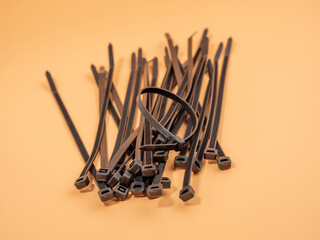 Black plastic cable ties on an orange background. Close-up.