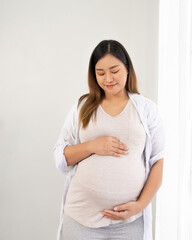 pregnant woman standing near window at home