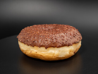 Chocolate donut with chocolate chips on a black background. close-up.