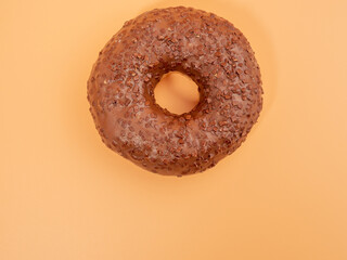 Chocolate donut with chocolate chips on an orange background. close-up.