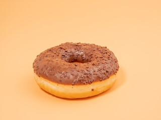 Chocolate donut with chocolate chips on an orange background. close-up.