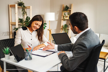Obraz premium Young woman successfully signs a contract with a business man at a business meeting