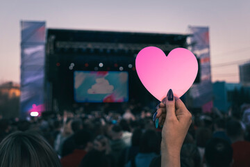 girl shows her pink heart to her favorite performer on stage. The concept of fan love for their...