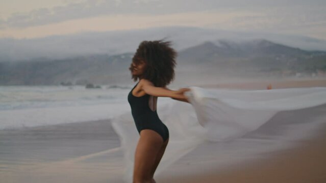 Girl spinning beach shawl summer twilight. Woman waving pareo smiling at camera.