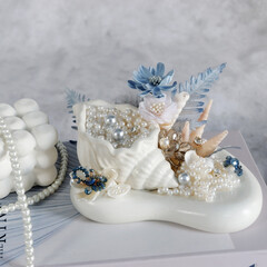 Engagement wedding ring in white concrete ring holder with aesthetic concrete tray and with sea shells and pearls. beautiful ocean themed ring place