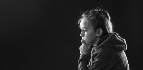 Stressed boy over black background, copy space. Childhood, bulling and family concept. Young boy suffering from anxiety.
