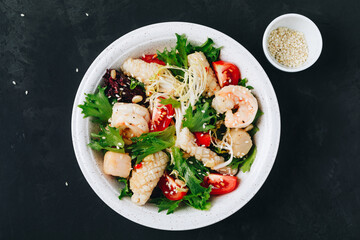 Seafood salad bowl. Green lettuce tomato salad with shrimps, scallop and squids