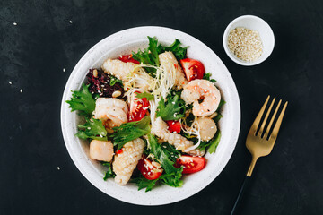 Seafood salad bowl. Green lettuce tomato salad with shrimps, scallop and squids