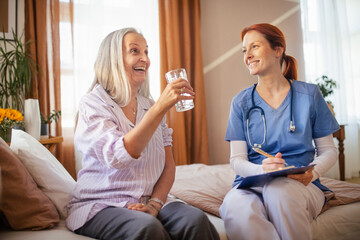 Nurse cosulting with senior her health condition, taking pills.