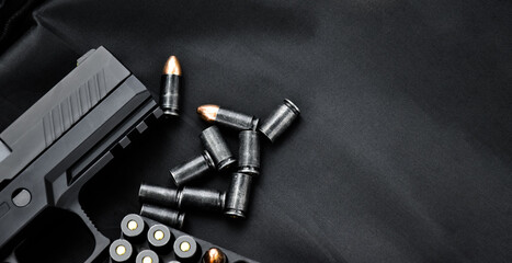 Automatic black 9mm pistol and bullets on black leather background, selective and soft focus, copy space.