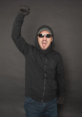 Screaming Man in the black hoody with hood wearing sunglasses with fist up