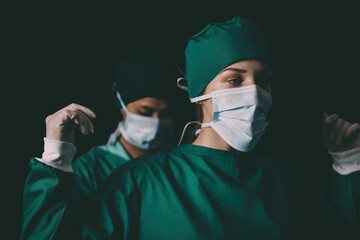 nurse help surgeon wearing medical uniform to protect body in operation. surgical doctor preparing to perform operation got help by staff. professional surgical woman support doctor putting uniform