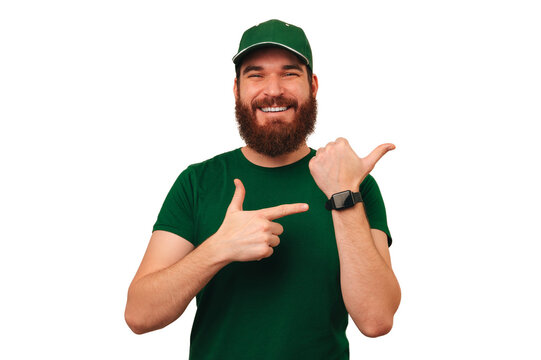 Cheerful delivery man wearing green uniform and smart watch points at it. He delivers in time.