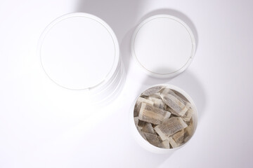 Closeup of a white Swedish snus can and portion snuff pouches against a white background