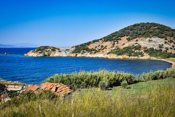 Fototapeta na wymiar A virgin bay in İzmir Foça. Aegean sea, maquis covered Aegean mountains, a destroyed stone house and natural vegetation. izmir ancient phokaia