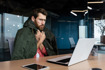 Office worker is freezing at work, there is no heating and broken office heating, businessman is...