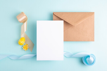 Aesthetic Easter composition. Empty card, easter eggs, colourful ribbons and envelope on pastel blue background, copy space.