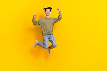 Fototapeta na wymiar Full body portrait of delighted overjoyed man jumping raise fists isolated on yellow color background