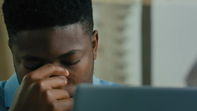 Close up African American ethnic businessman adult middle-aged man feel pain headache migraine eyes strain discomfort after computer work in office sick ill employee suffer painful head health problem