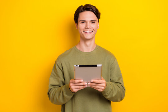 Photo of successful positive man freelancer blogger wear trendy khaki clothes buy new gadget isolated on yellow color background