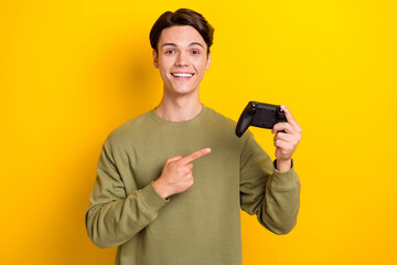 Photo of glad attractive man addicted gamer wear khaki clothes demonstrate playstation isolated on yellow color background