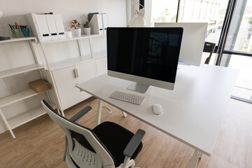 White table and chair with computer monitor and modern file cabinet in white home office
