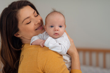 Young mother holding her baby in the bedroom