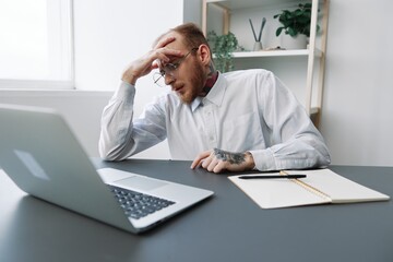 Fototapeta premium A man in a wheelchair a businessman in the office works, severe fatigue and emotional burnout, integration into society, the concept of work a person with disabilities