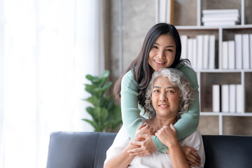 Asian mother and son spending vacation in living room Show your love for each other by embracing each other warmly and happily at home.