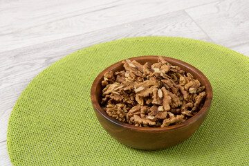 peeled walnuts in a wooden cup on a green napkin