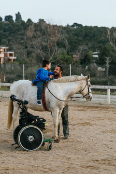 Boy with disabilities having his equine therapy with an instructor.