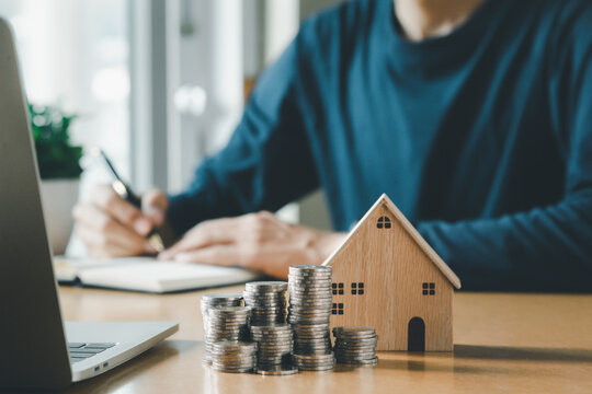 Man Hand Holding Coin On Wood Table. Save Money And Financial Investment And Saving Money For Buying House, Financial Plan Home Loan Concept.