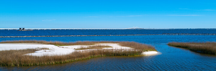 Pensacola Bay Tranquil Seascape with views of bright white sand dune island and the blue horizon over the bridge in Florida, USA