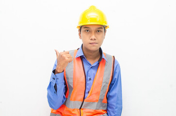 asian construction worker wearing yellow safety helmet and vest smiling and pointing finger with happy and shocked expression. billboard model advertisment concept. 