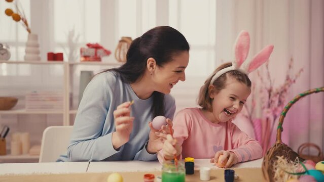 Mom and little daughter decorating eggs, preparation for Easter celebration