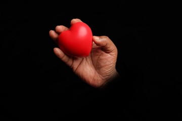 Asian dark skin top view two hand holding making red hart love shape sign on black background