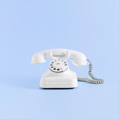 Minimal retro office concept with white vintage phone on violet and light blue background. Retro futuristic telephone aesthetic, promotion, communication, advertisement creative idea.